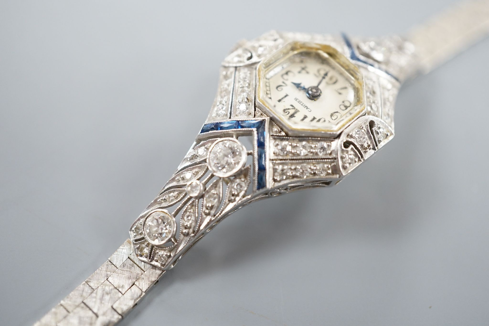 A mid 20th century white metal, synthetic sapphire? and diamond set cocktail watch, with Bucherer manual wind movement and dial bearing the signature Cartier, on a 14k white metal bracelet, case diameter 22mm, gross weig